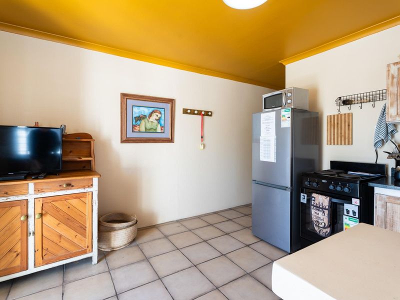 A functional kitchen area featuring tiled flooring, built-in cabinetry, and a freestanding stove with an extractor fan.