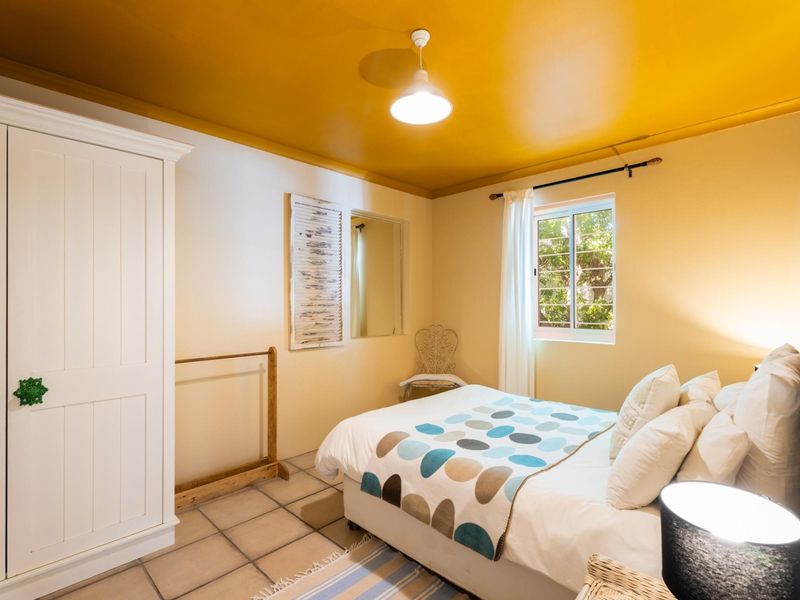 A bedroom featuring tiled flooring, a built-in wardrobe, and a window with security bars, finished with a bold yellow ceiling.