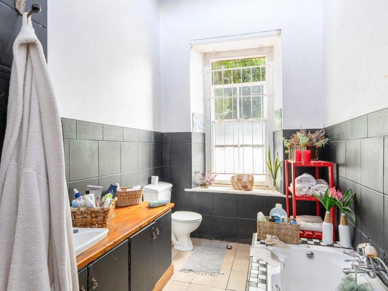 Bathroom featuring a built-in vanity, bathtub, and dark tiled wall accents, offering a functional layout with natural light from the window.