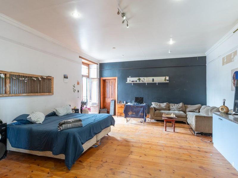 Spacious bedroom featuring original hardwood flooring, crown molding, and recessed lighting, offering a versatile layout with direct access to an outdoor area.