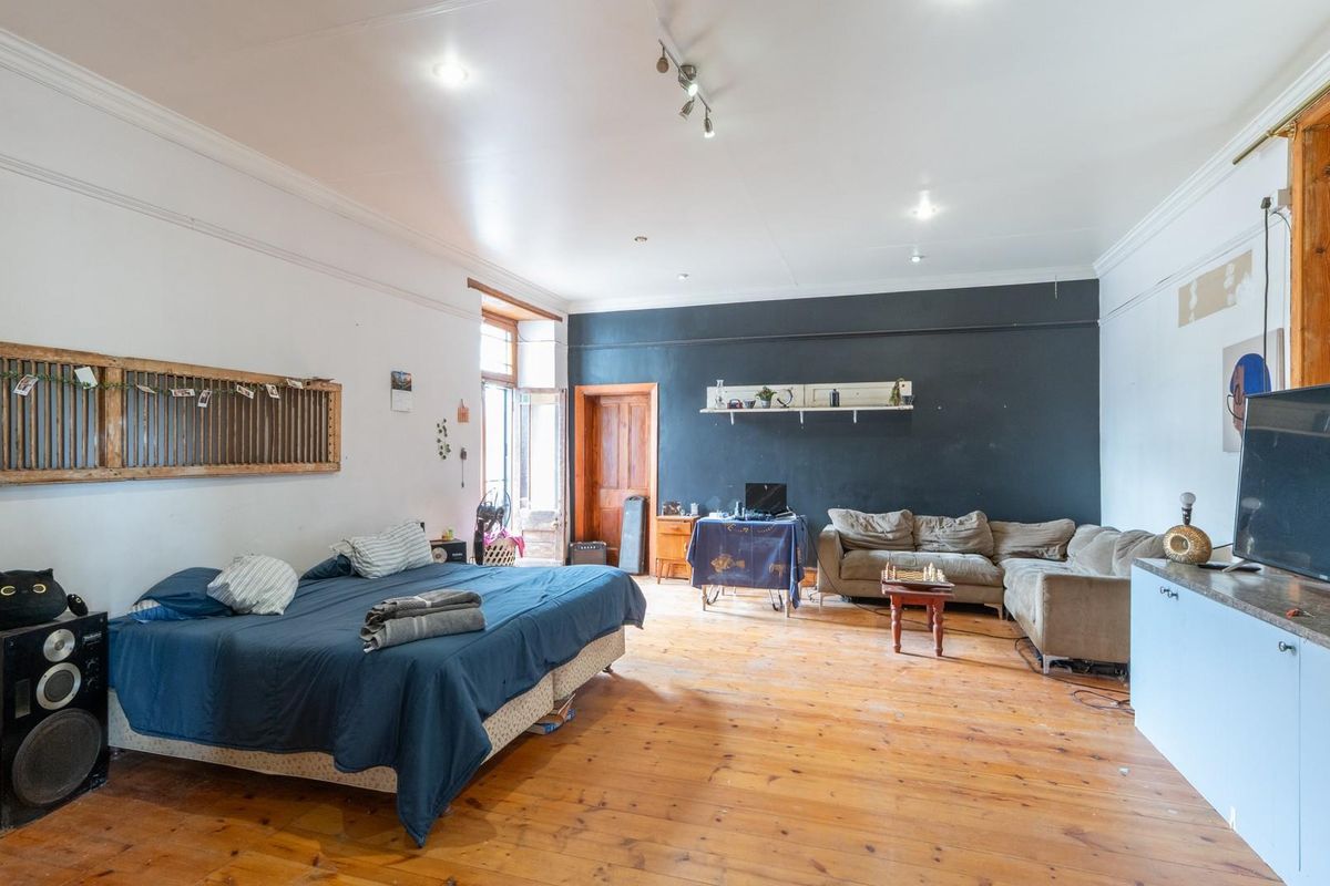 Spacious bedroom featuring original hardwood flooring, crown molding, and recessed lighting, offering a versatile layout with direct access to an outdoor area.