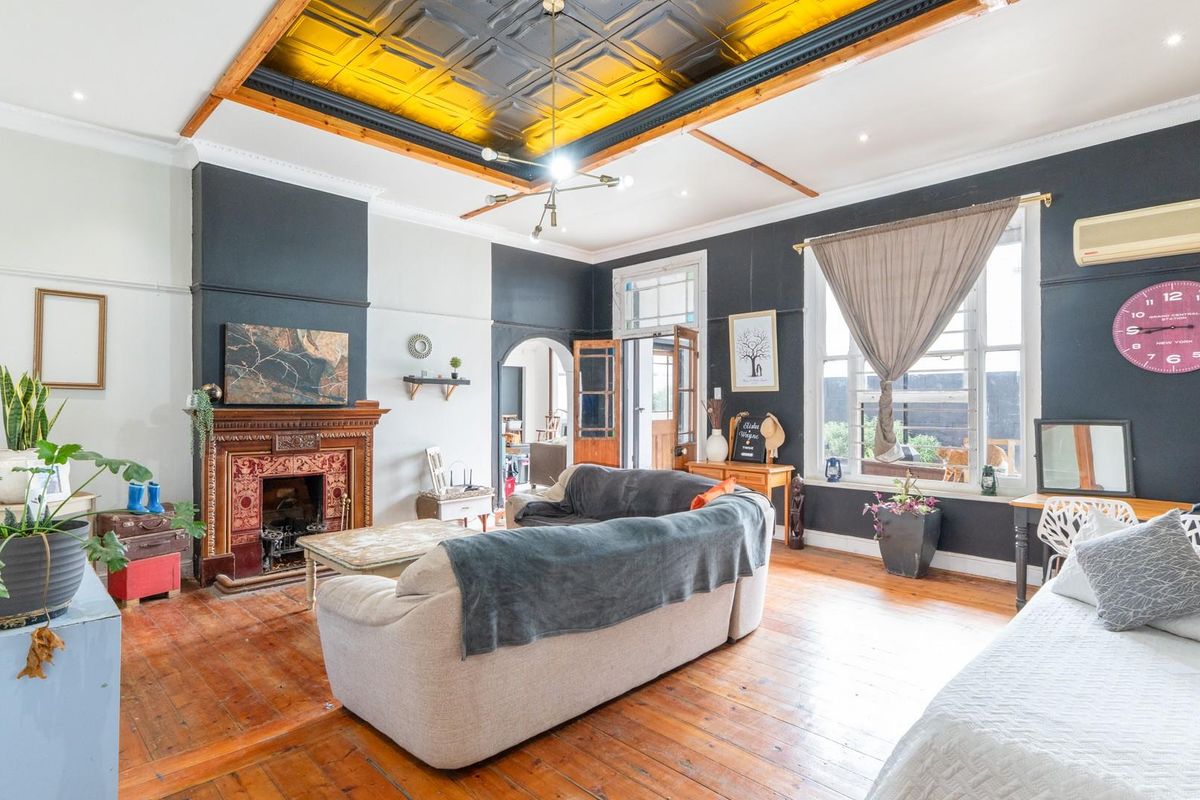 Spacious living room featuring original hardwood floors, an ornate fireplace, and a distinctive coffered ceiling with modern lighting.