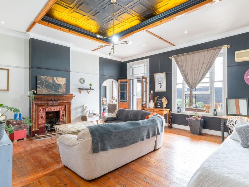 Spacious living room featuring original hardwood floors, an ornate fireplace, and a distinctive coffered ceiling with modern lighting.