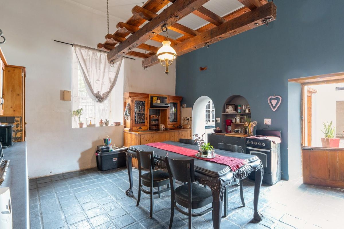 Rustic kitchen featuring exposed timber ceiling beams, stone tile flooring, built-in wooden cabinetry, and charming arched wall niches with a stable door entrance.