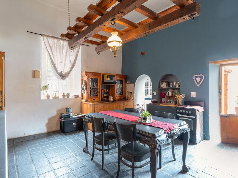 Rustic kitchen featuring exposed timber ceiling beams, stone tile flooring, built-in wooden cabinetry, and charming arched wall niches with a stable door entrance.