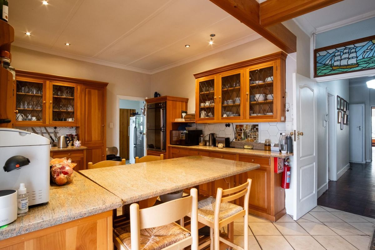 A traditional kitchen featuring warm timber cabinetry, granite countertops, built-in oven, and a decorative stained glass transom window above the doorway.