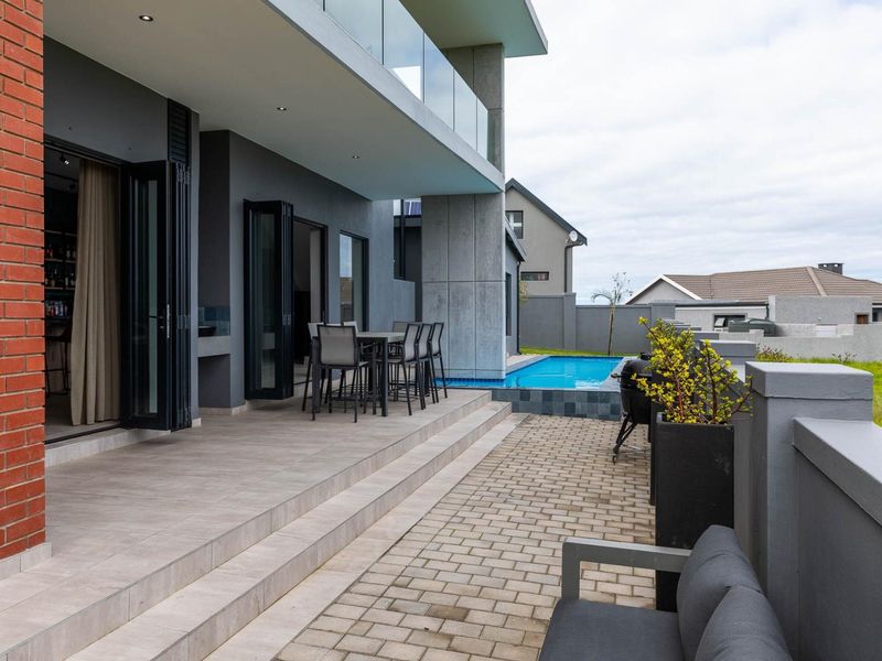 Modern covered patio featuring tiled flooring, glass balustrades, and seamless access to the swimming pool area, perfect for outdoor entertaining.