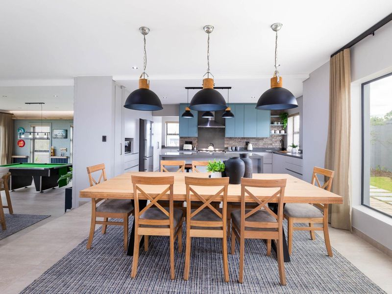 Spacious open-plan dining and kitchen area featuring modern cabinetry, a central island, and large windows providing natural light and garden views.