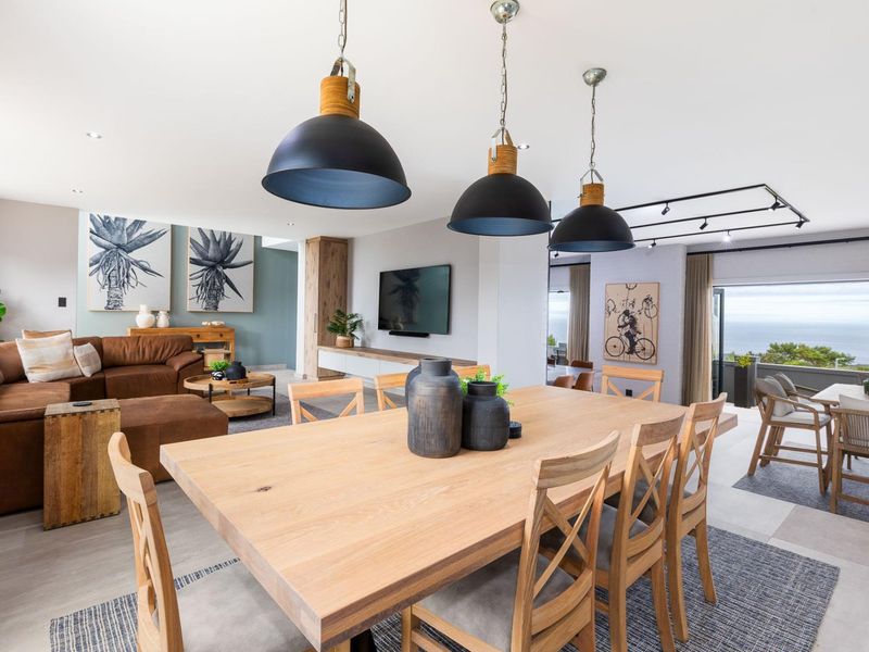 Spacious open-plan living and dining area featuring modern pendant lighting, built-in cabinetry, and seamless access to an outdoor balcony with scenic views.