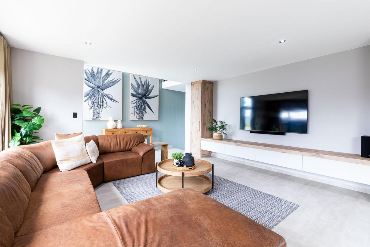 Modern living room featuring tiled flooring, recessed downlights, and a sleek built-in media console with integrated cabinetry.