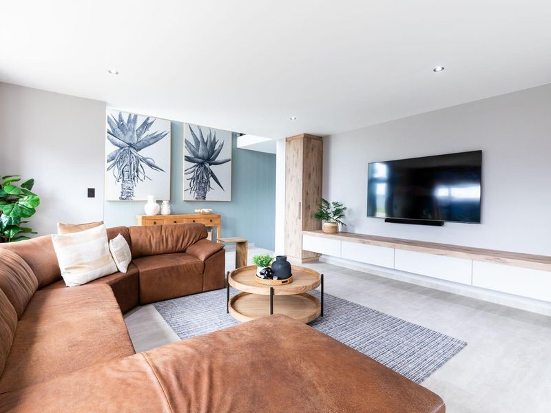 Modern living room featuring tiled flooring, recessed downlights, and a sleek built-in media console with integrated cabinetry.
