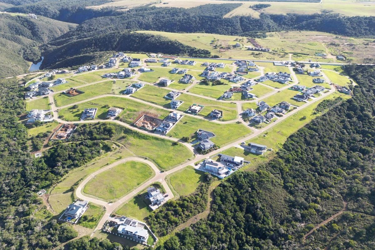 An aerial view of a residential estate development featuring paved roads, established housing plots, and surrounding natural landscape.