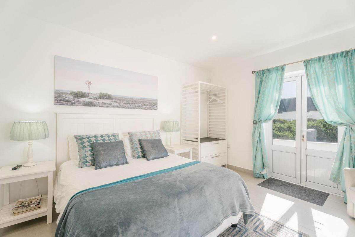Bright bedroom featuring tiled flooring, recessed lighting, and direct access to the outdoors through white french doors.