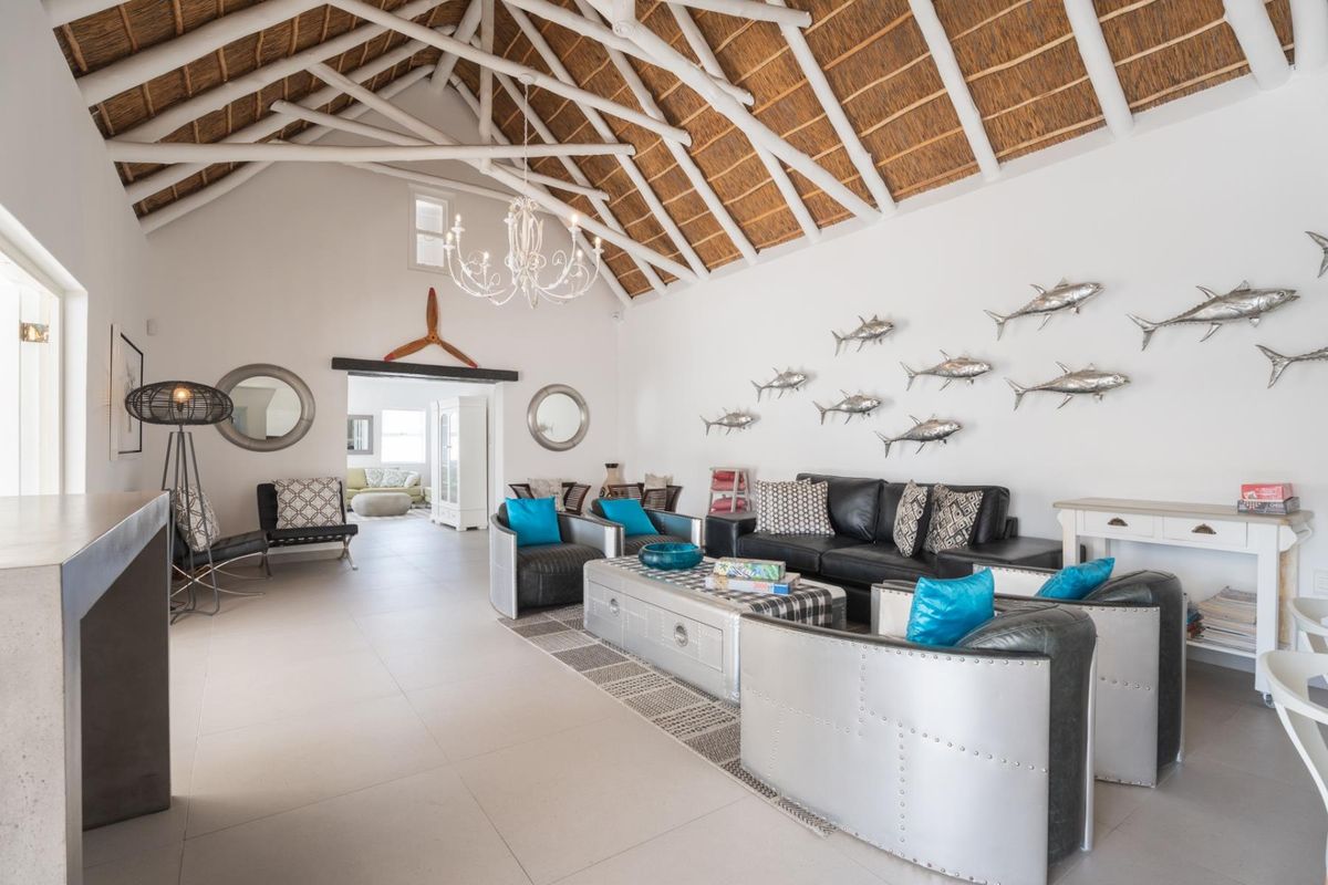 Spacious living area featuring a high vaulted ceiling with exposed timber rafters and traditional thatch roofing, complemented by neutral tiled flooring.