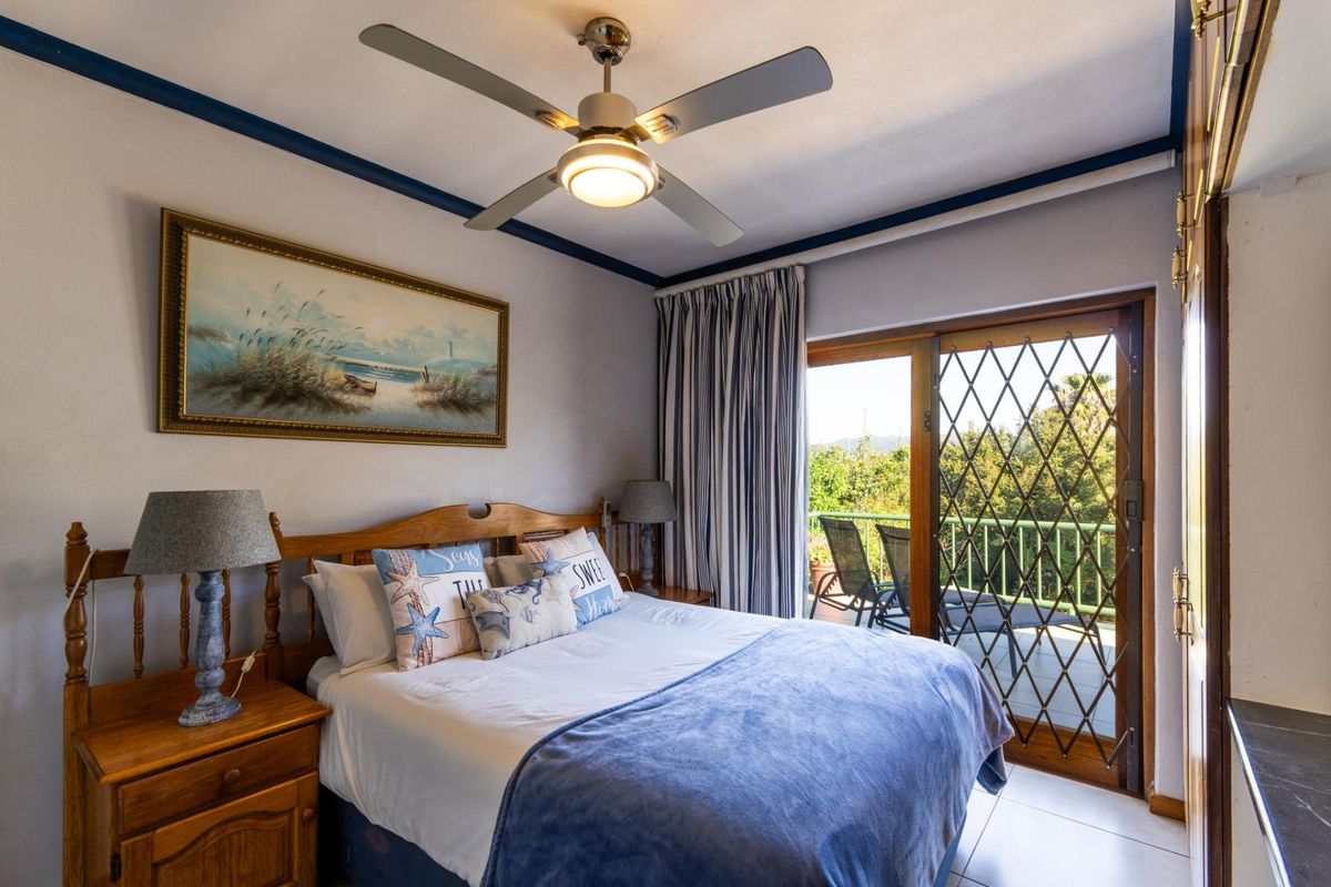 A well-maintained bedroom featuring a ceiling fan, tiled flooring, and a sliding glass door providing access to a private balcony.