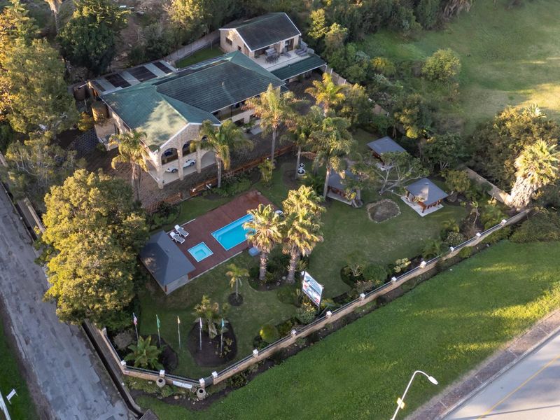 Aerial view of the guest house property featuring a swimming pool, wooden decking, multiple gazebos, and a well-maintained landscaped garden.