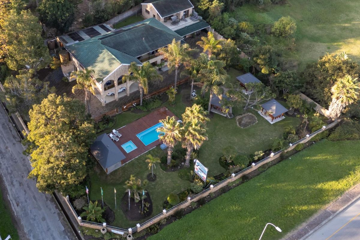 Aerial view of the guest house property featuring a swimming pool, wooden decking, multiple gazebos, and a well-maintained landscaped garden.