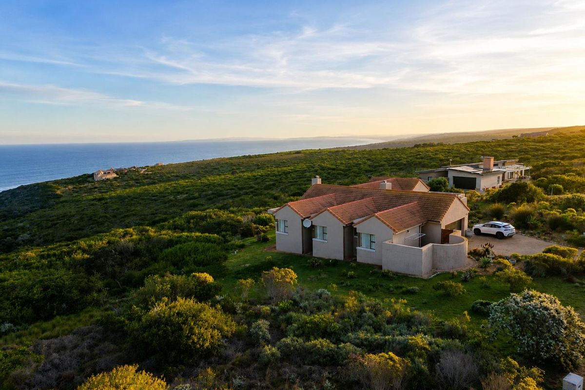Aerial view of a residential property situated in a coastal landscape, featuring a tiled roof and expansive natural surroundings.