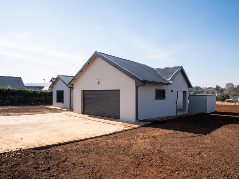 A modern townhouse exterior featuring a metal roof, a secure garage door, and a concrete driveway set against a clear sky.