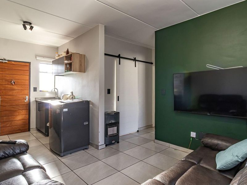 Open-plan living area featuring tiled flooring, a compact kitchen corner, and a sliding barn door leading to adjacent rooms.