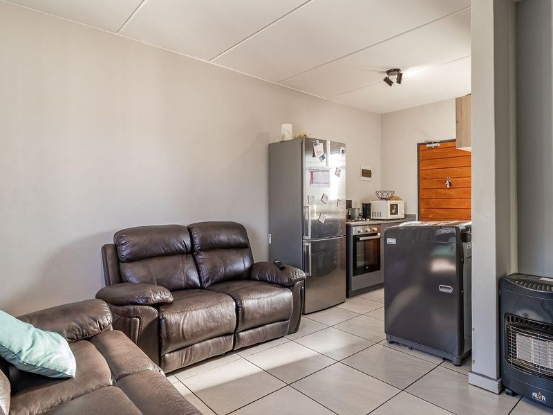Open-plan living area featuring tiled flooring and a compact kitchen space with built-in oven and hob, creating a functional and connected living environment.