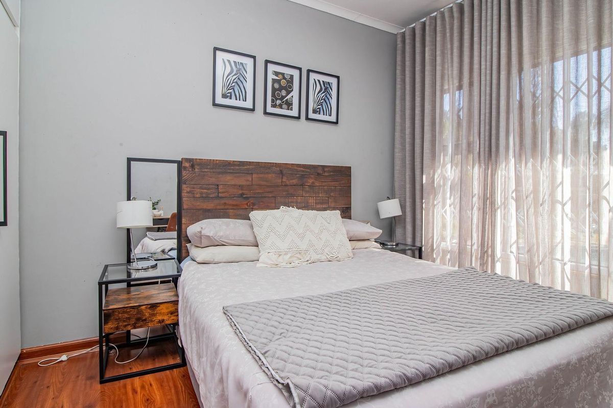 A well-maintained bedroom featuring laminate flooring, a built-in wardrobe, and a security gate over the window for added peace of mind.
