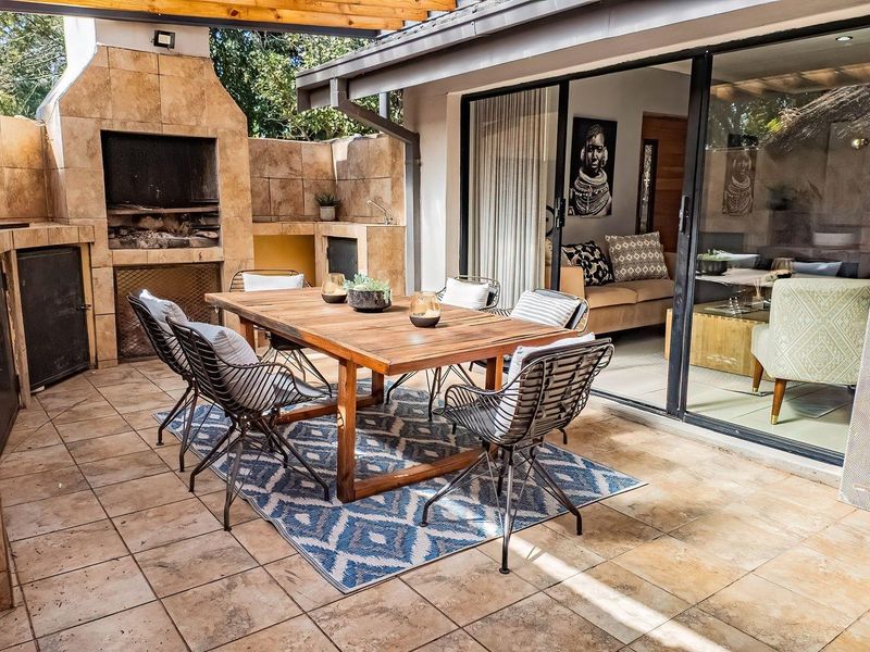 A covered outdoor patio featuring a built-in braai, tiled flooring, and large sliding glass doors providing seamless access to the interior living space.