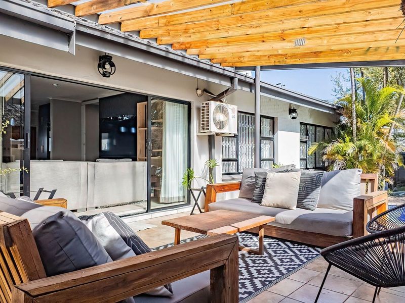 A covered outdoor patio featuring a timber pergola, tiled flooring, and direct access to the interior living space through sliding glass doors.