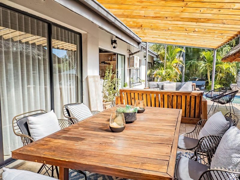 A spacious covered patio featuring a timber pergola, tiled flooring, and large sliding glass doors providing seamless indoor-outdoor flow.