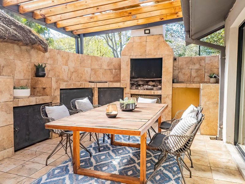 Covered outdoor patio featuring a built-in braai, tiled wall finishes, and a timber pergola, providing a functional space for alfresco dining.
