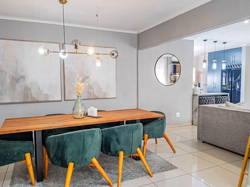 An open-plan dining area featuring modern pendant lighting and tiled flooring, seamlessly flowing into a contemporary kitchen space.