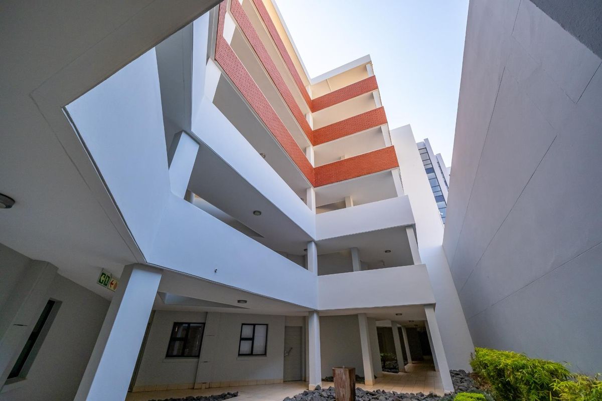 A view of the apartment building exterior featuring multi-level balconies with brick accents and concrete structural elements.