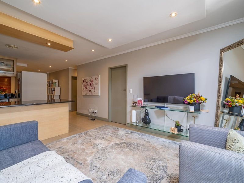 Open-plan living area featuring a modern kitchen with granite countertops, recessed lighting, and neutral tiled flooring, creating a cohesive and functional living space.