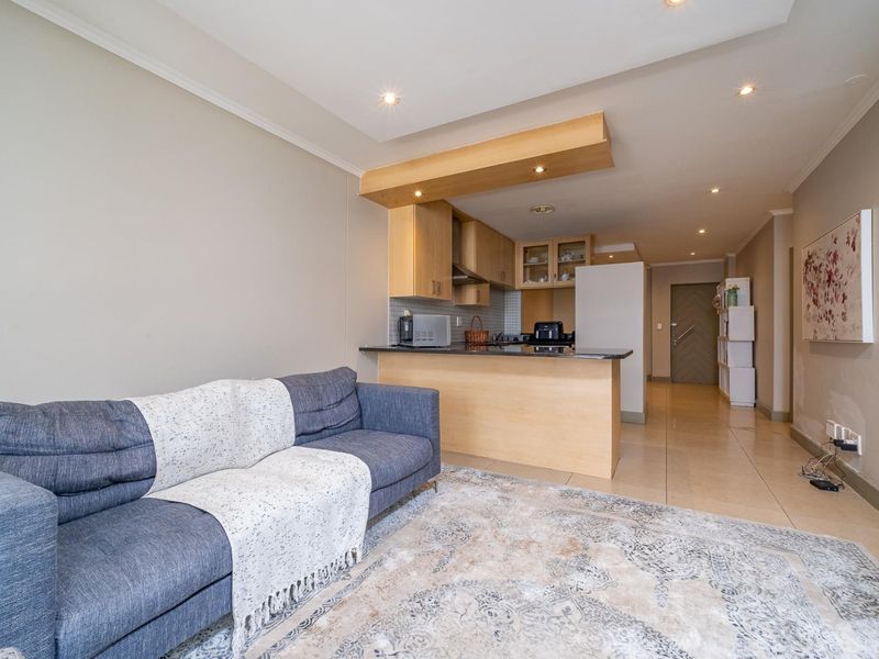 Open-plan living area featuring a functional kitchen with built-in cabinetry, granite countertops, and tiled flooring throughout the combined space.