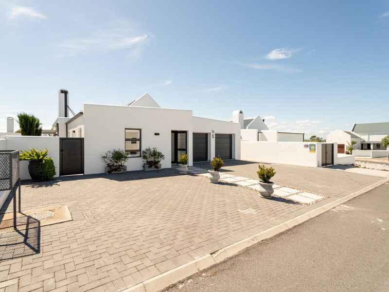 Modern front facade featuring a paved driveway, double garage, and clean white exterior finishes with secure boundary walling.