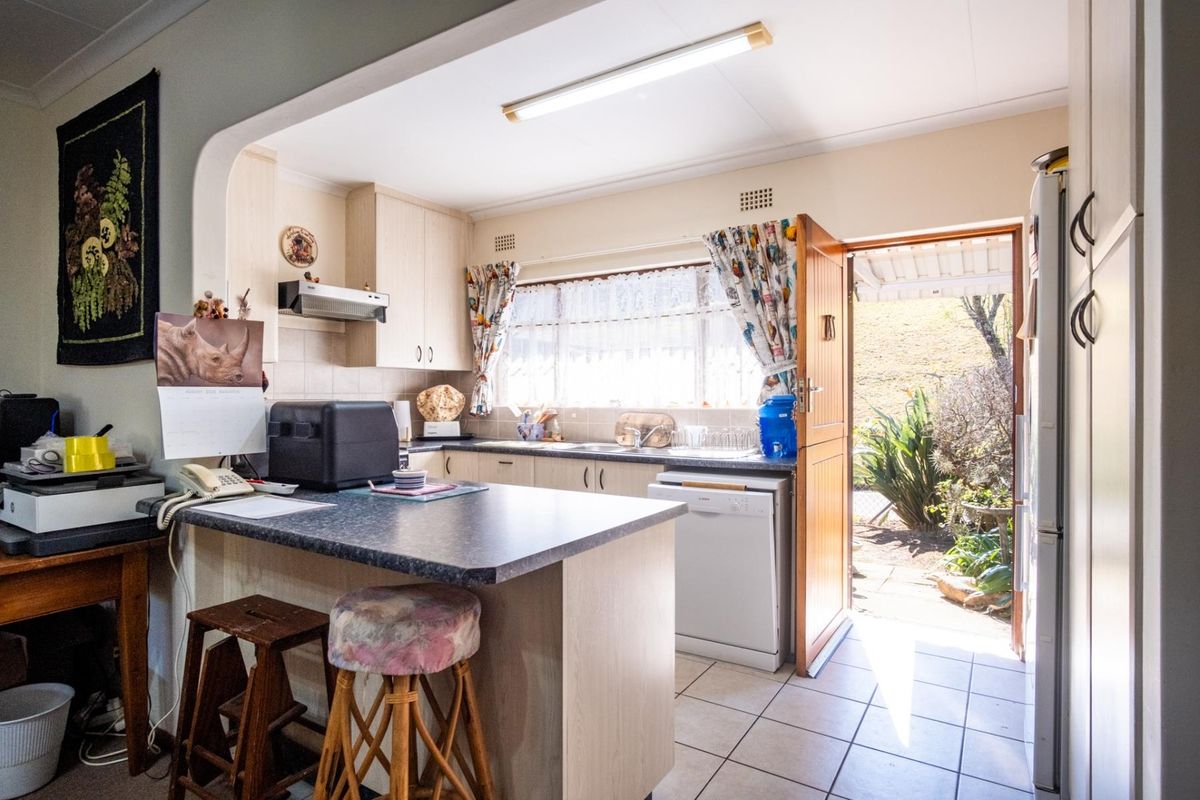 A functional kitchen featuring laminate cabinetry, tiled flooring, and a stable door providing direct access to the rear garden area.