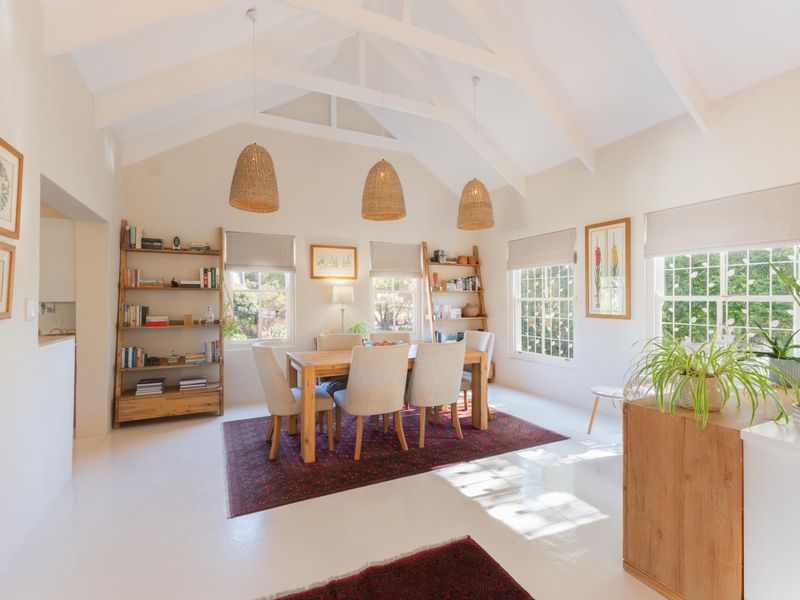 Bright and airy dining room featuring a high vaulted ceiling with exposed rafters, large sash windows, and clean, neutral finishes throughout.