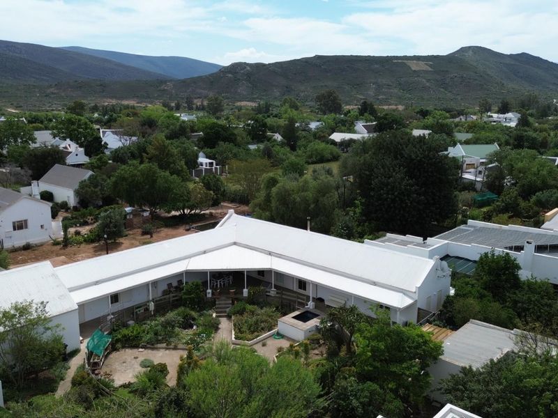 Aerial view of a residential property featuring a white metal roof, a central garden courtyard, and a covered patio area set within a scenic landscape.