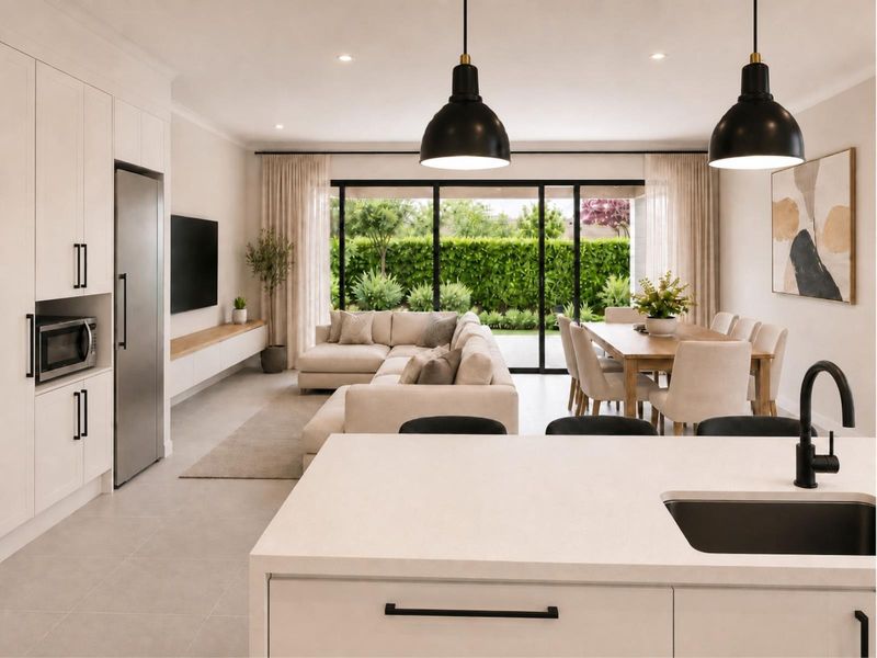 Modern open-plan living area featuring a sleek kitchen with island, dining space, and seamless flow to the outdoor patio through large sliding glass doors.