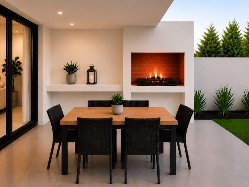 A modern covered patio featuring a built-in fireplace, recessed lighting, and seamless access to the interior through large sliding glass doors.