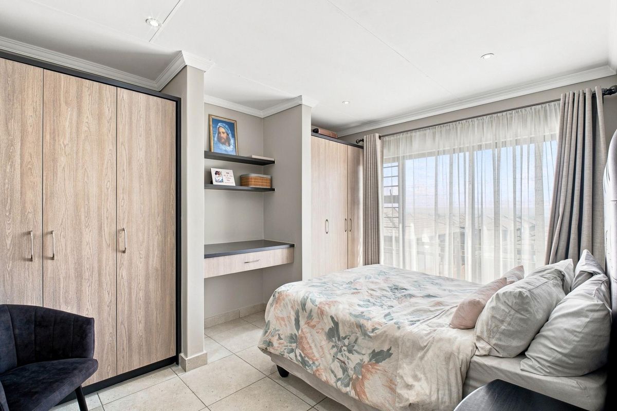 A well-maintained bedroom featuring modern built-in cupboards, a functional built-in desk, tiled flooring, and recessed downlighting, offering a clean and organized living space.