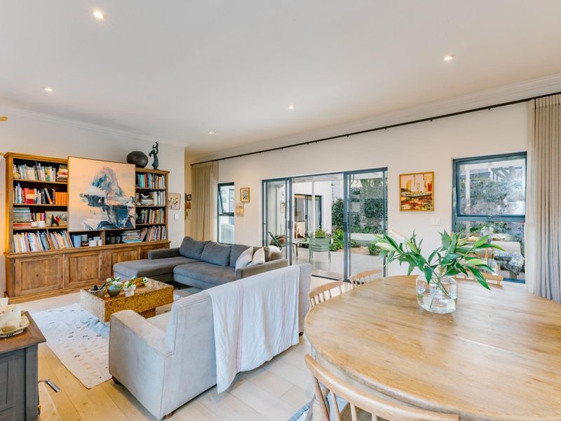 Spacious open-plan living and dining area featuring timber flooring, recessed lighting, a wood-burning stove, and large sliding doors opening to an outdoor patio.