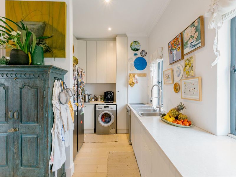 A functional laundry area featuring built-in cabinetry, a stainless steel sink with mixer tap, and space for a washing machine.
