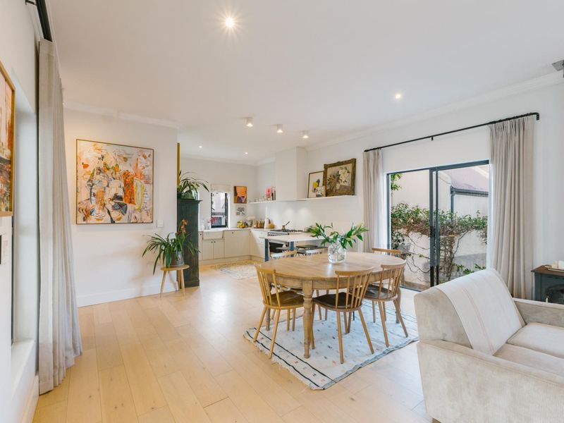Bright open-plan living and dining area featuring light hardwood floors, a wood-burning stove, and seamless access to the outdoor patio through sliding glass doors.