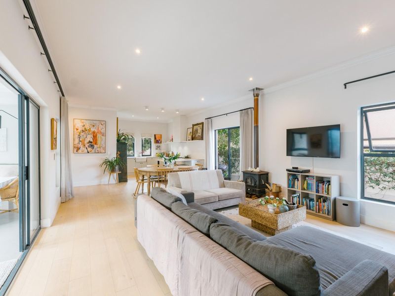 Spacious open-plan living and kitchen area featuring timber flooring, a wood-burning stove, and large sliding glass doors providing access to the outdoors.
