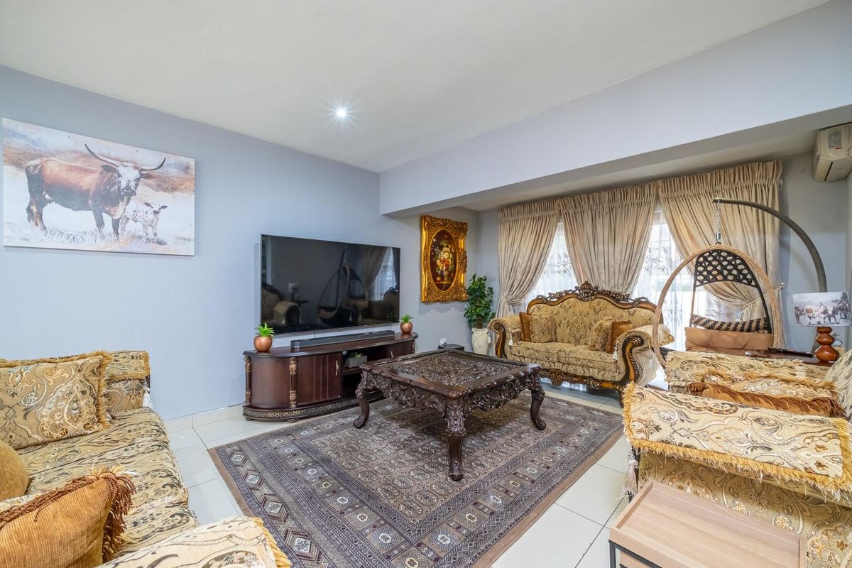A spacious living room featuring neutral wall tones, tiled flooring, and a wall-mounted air conditioning unit, providing a comfortable and functional living space.