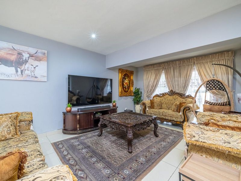 A spacious living room featuring neutral wall tones, tiled flooring, and a wall-mounted air conditioning unit, providing a comfortable and functional living space.