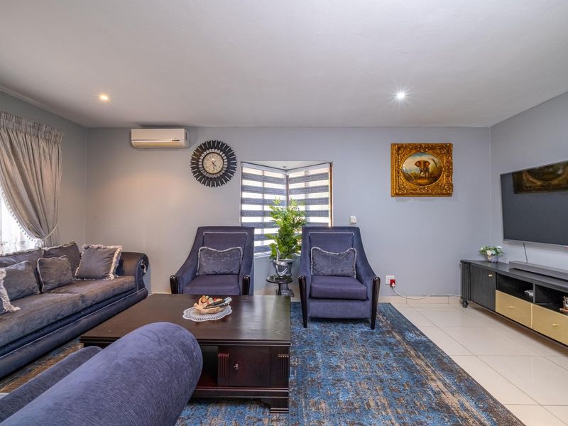 A well-maintained living room featuring tiled flooring, recessed downlighting, and a split-system air conditioning unit, providing a comfortable and functional space.