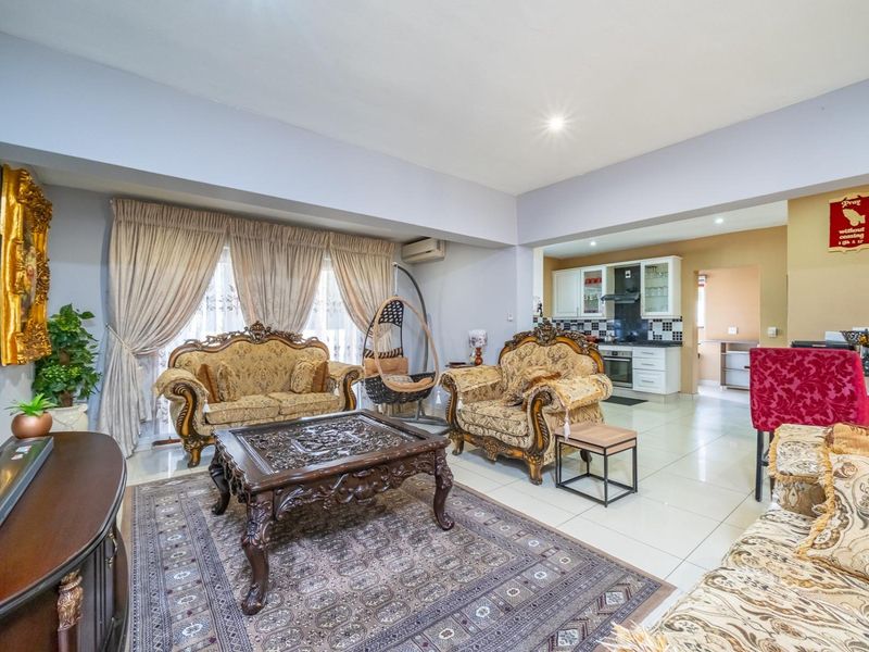 Open-plan living area featuring tiled flooring, recessed lighting, and a connected kitchen with built-in cabinetry and appliances.
