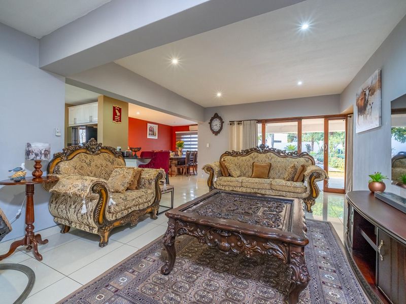 Spacious open-plan living area featuring tiled floors, recessed lighting, and seamless flow to the dining room and kitchen, with access to the outdoor patio.